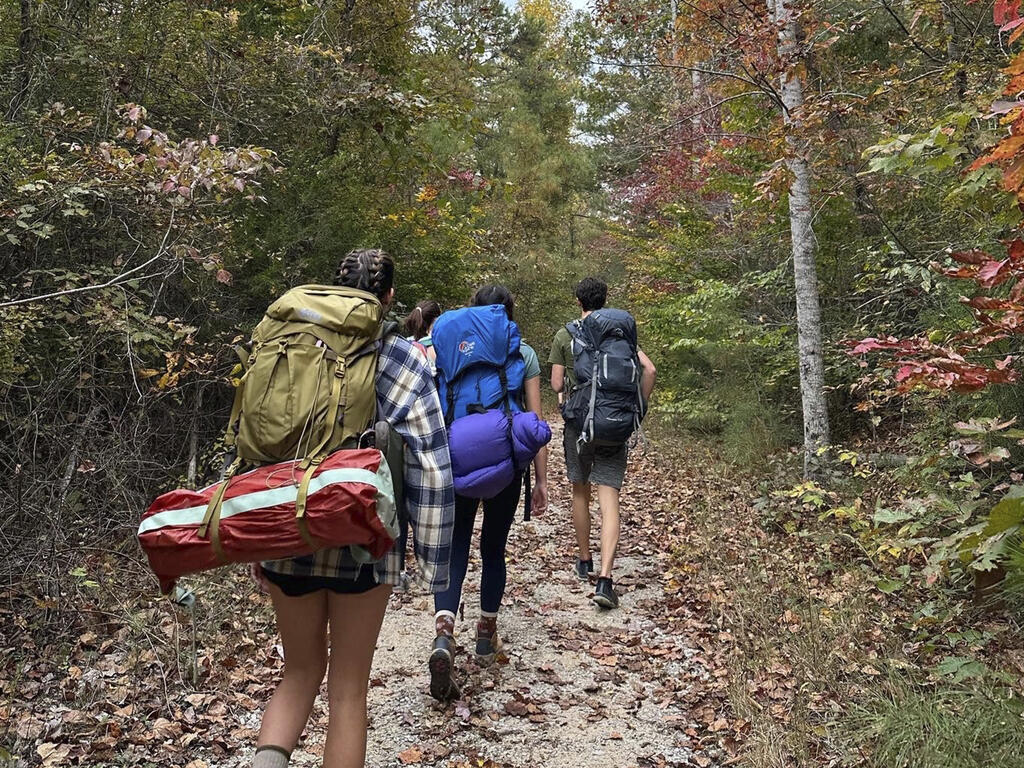 three students backpacking on a trail