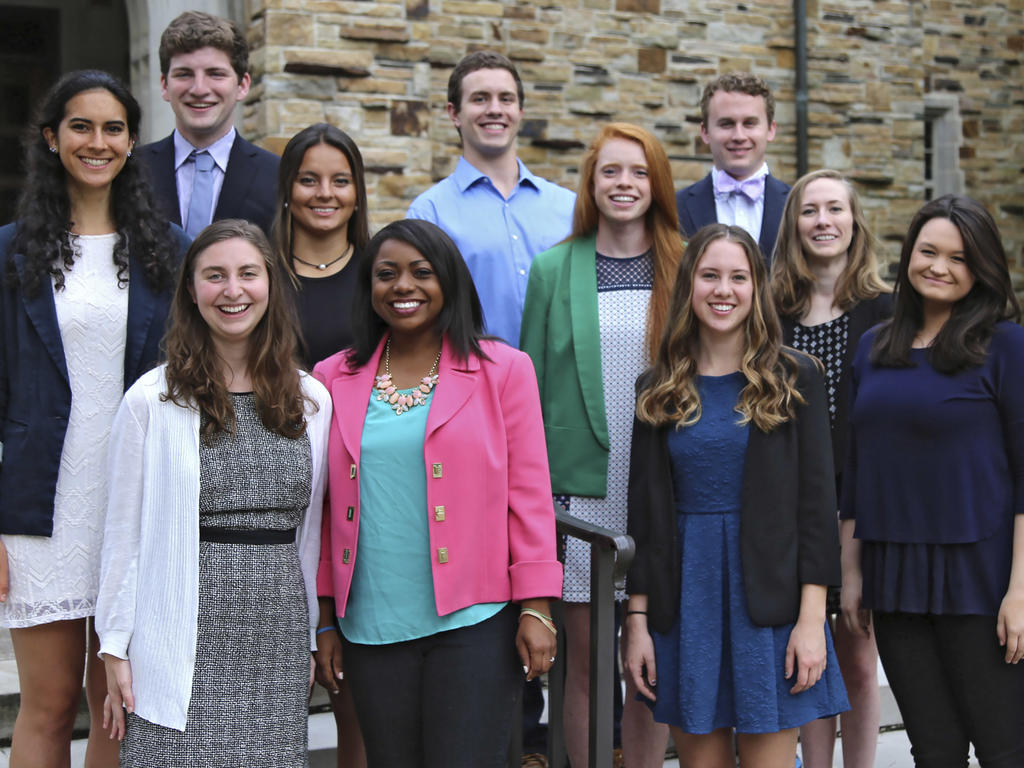 a diverse group of students in business attire standing outside of an academic building