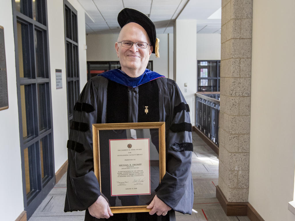 Dr. Michael Drompp in academic robes holding a certificate