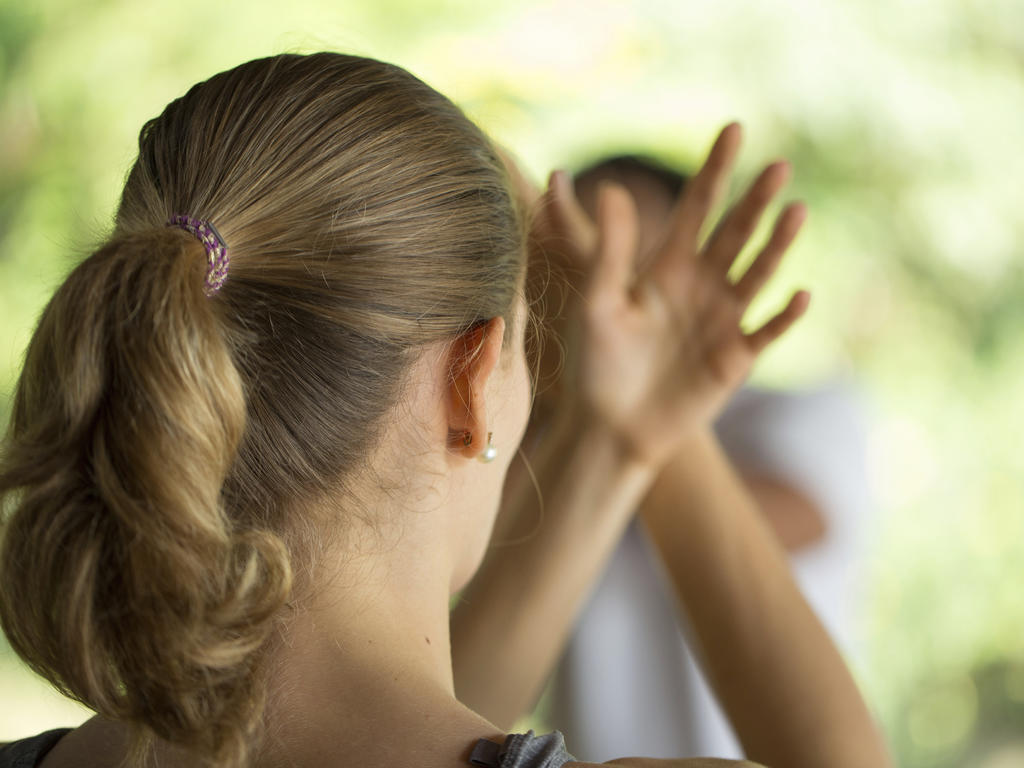 a female's ponytail with her hands making zen motions in the blurred out background