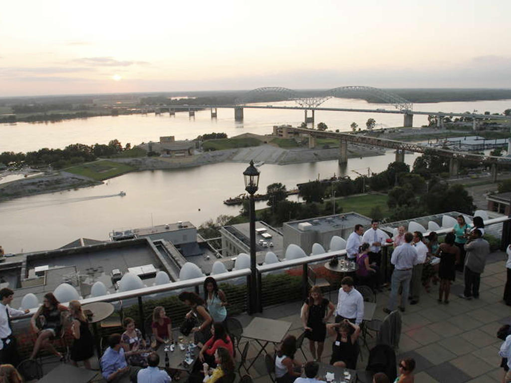 a panoramic image showing a diverse group of young adults socializing near the Memphis river and bridge
