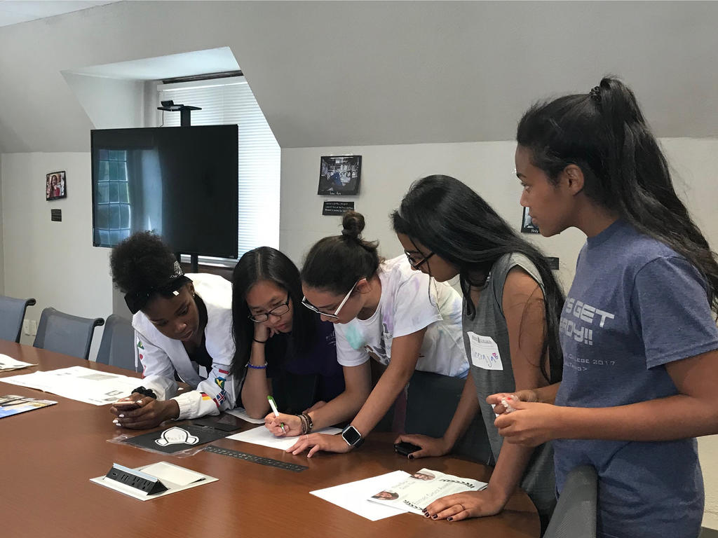 group of diverse girls reviewing materials on a conference room table