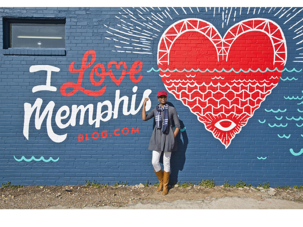 a student standing in front of a mural that says "I love Memphis" with a heart on it